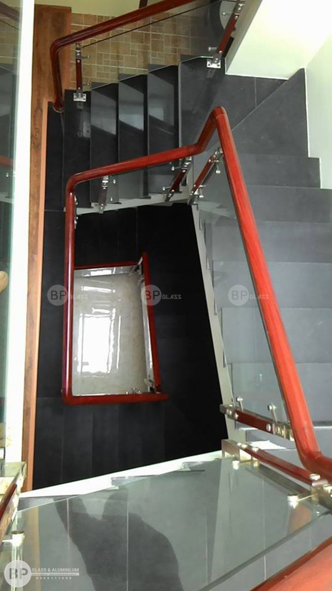 Toàn cảnh cầu thang kính tay vịn gỗ nhìn từ trên xuống